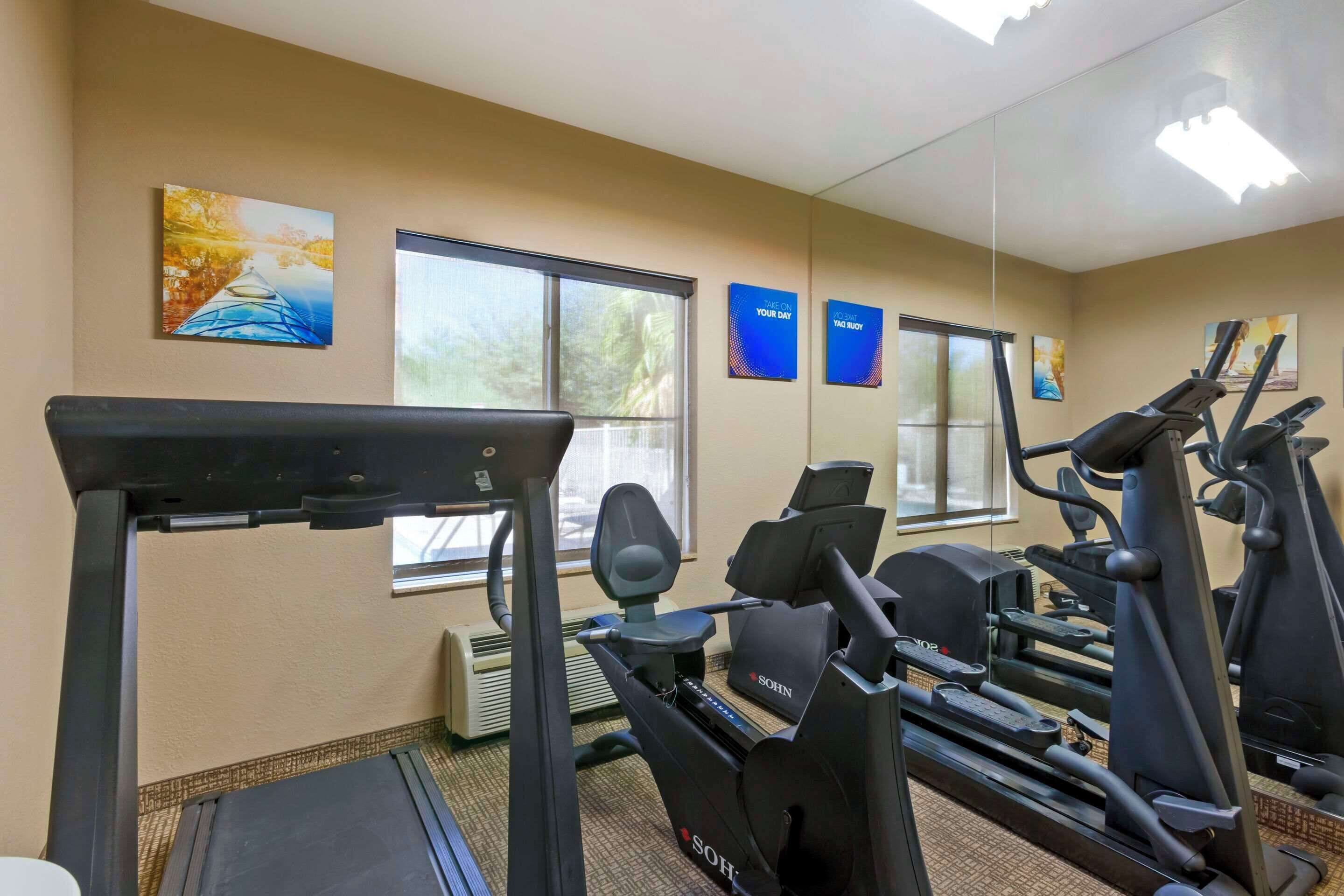 Un gimnasio con cintas de correr, elípticas y un espejo grande.