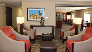 A hotel lobby with two armchairs, a small table, a lamp, and a framed picture on the wall. - Comfort Inn Green Valley I-19 (Green Valley)