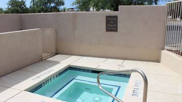 A swimming pool with a lifeguard warning sign, a metal pool ladder, and tiled steps leading into the pool.