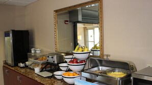 A buffet setup with various food items and a mirror on the wall.