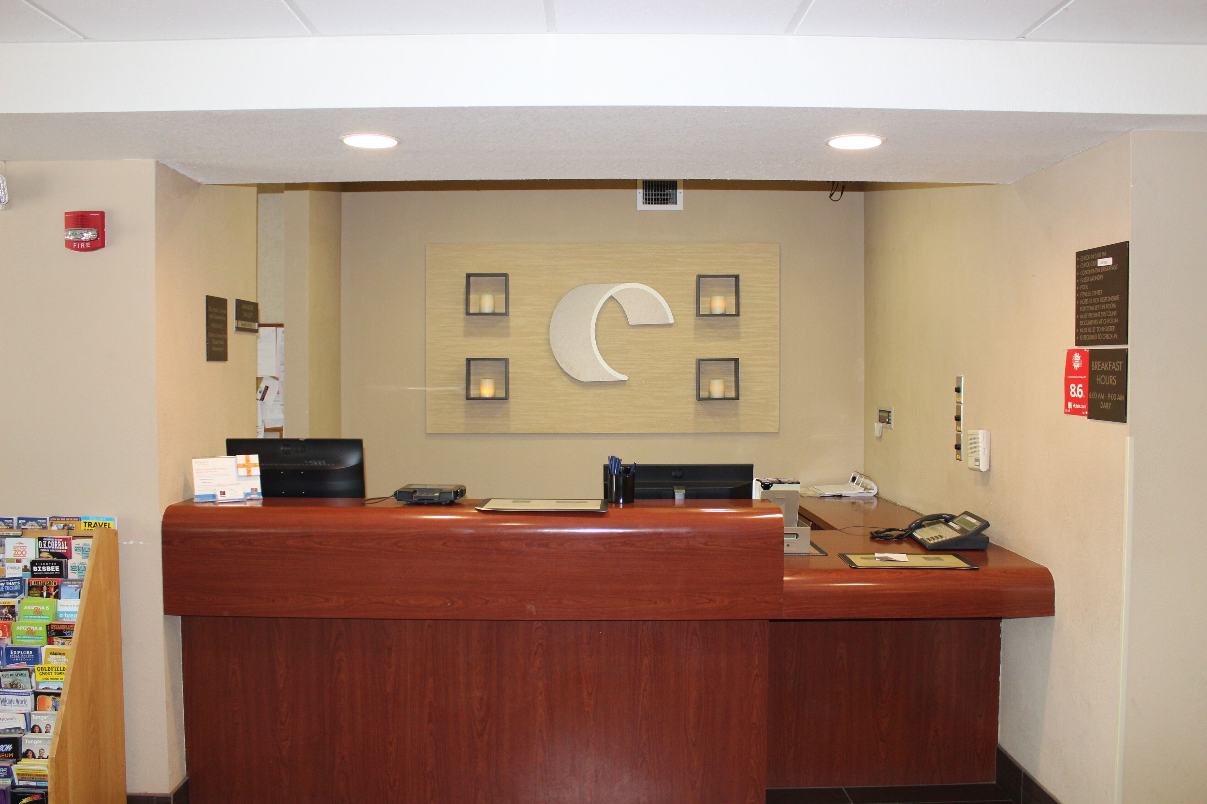 A hotel reception desk with a wooden counter, a crescent moon decoration, and a bulletin board with travel brochures.