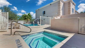 A swimming pool with a tiled edge, a white fence, and a building in the background.