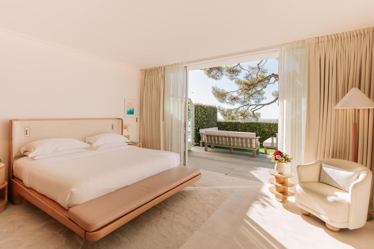A hotel room with a large bed, a sofa, and a view of the outdoors.