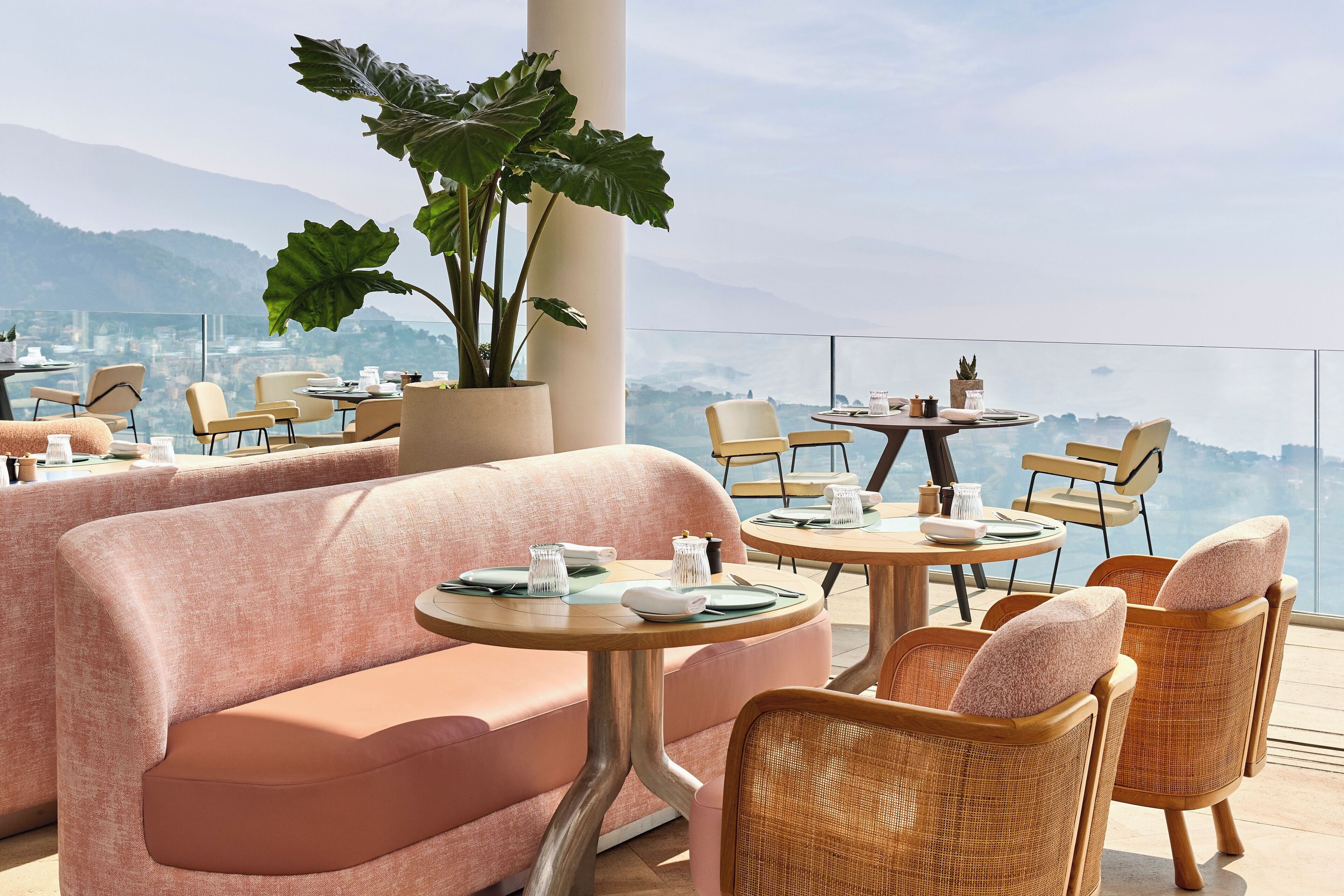 A rooftop terrace with seating arrangements, a large potted plant, and a view of the cityscape.