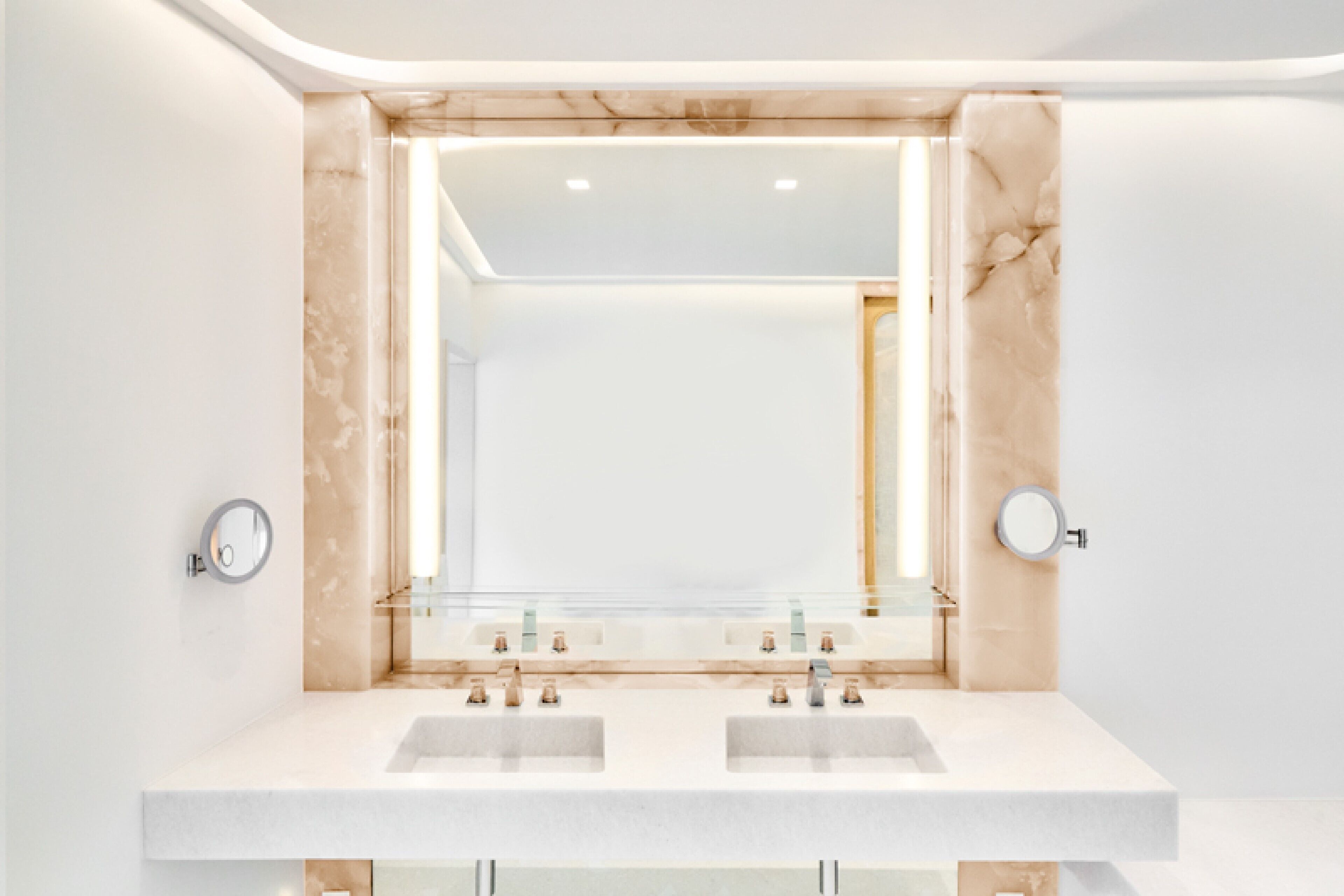 Un baño moderno con dos lavamanos, un espejo grande y detalles de mármol.