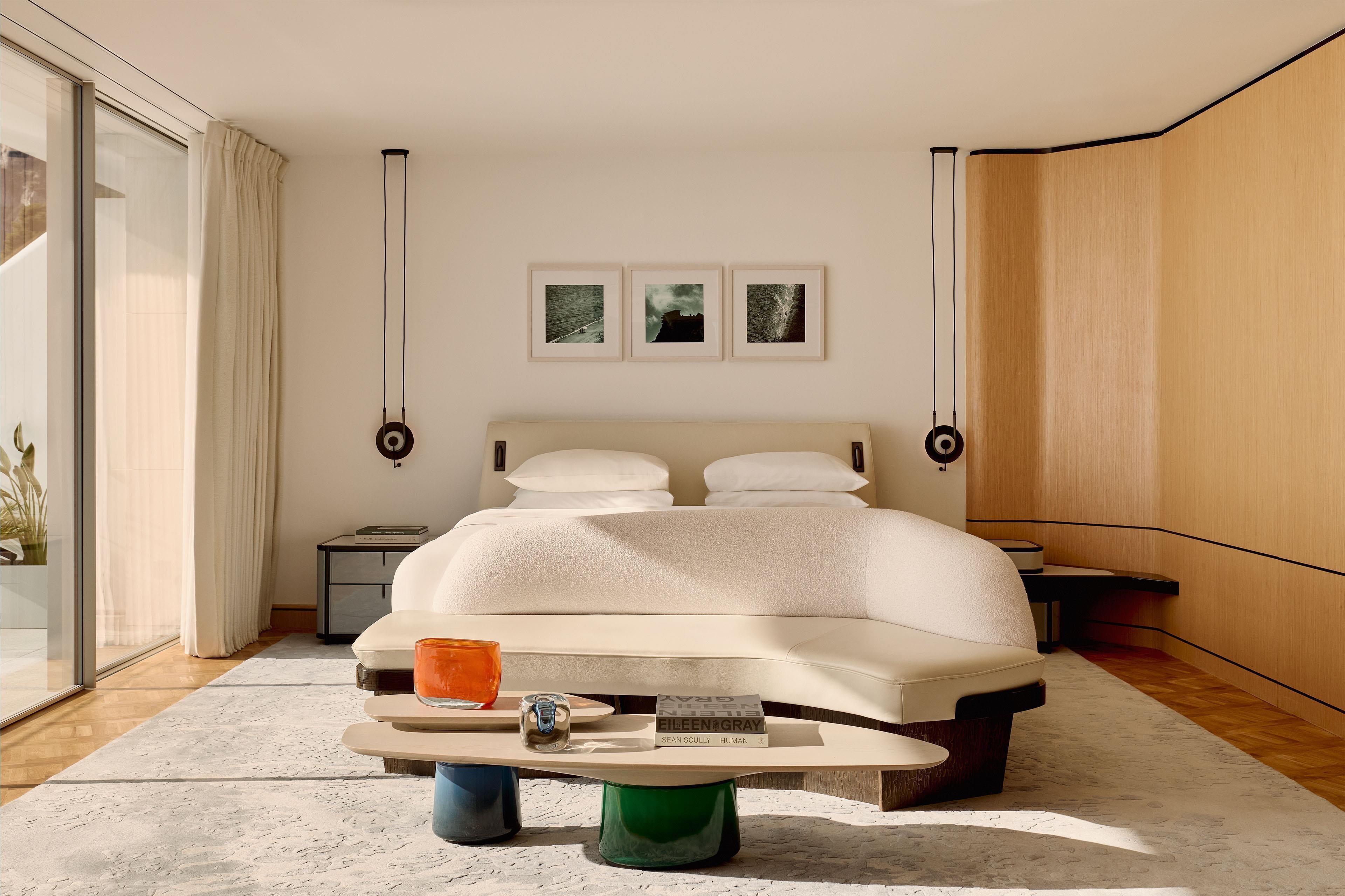 A modern bedroom with a large bed, bedside tables, a reading lamp, and framed pictures on the wall.