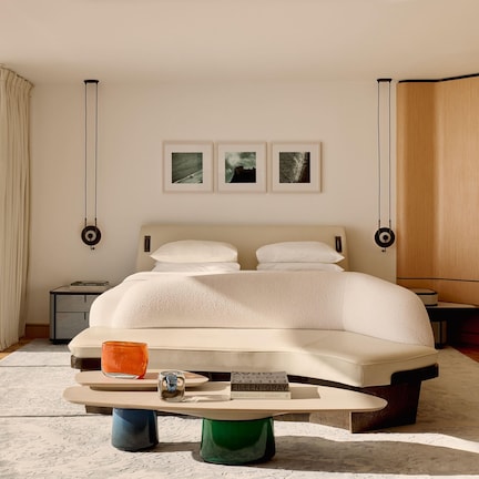 A modern bedroom with a large bed, bedside tables, a reading lamp, and framed pictures on the wall.