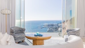 A modern living room with a large glass door leading to a balcony with a city view. - The Maybourne Riviera, Maybourne  (Roquebrune-Cap-Martin)