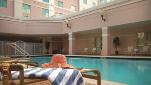 Un espace piscine d’hôtel avec un fauteuil de relaxation, une serviette à rayures et une vue sur le bâtiment de l’hôtel.