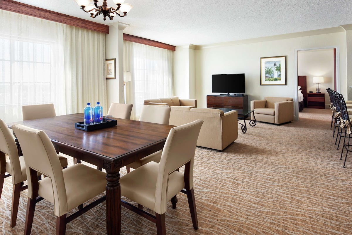 Une chambre d’hôtel comprenant un coin repas, un ensemble de meubles de salon, un téléviseur et un sol recouvert de moquette.