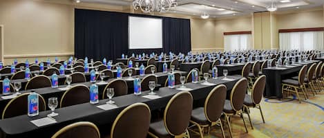 A conference room with rows of tables, chairs, and water bottles.