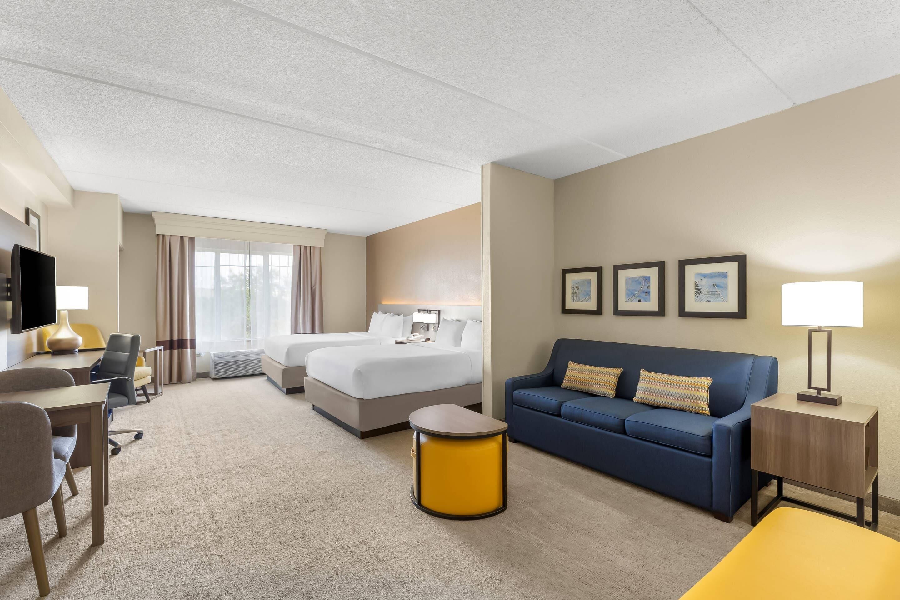 Une chambre d’hôtel avec un lit, un canapé, un bureau et une chaise.