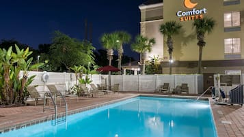Una piscina al aire libre, sillones reclinables de piscina