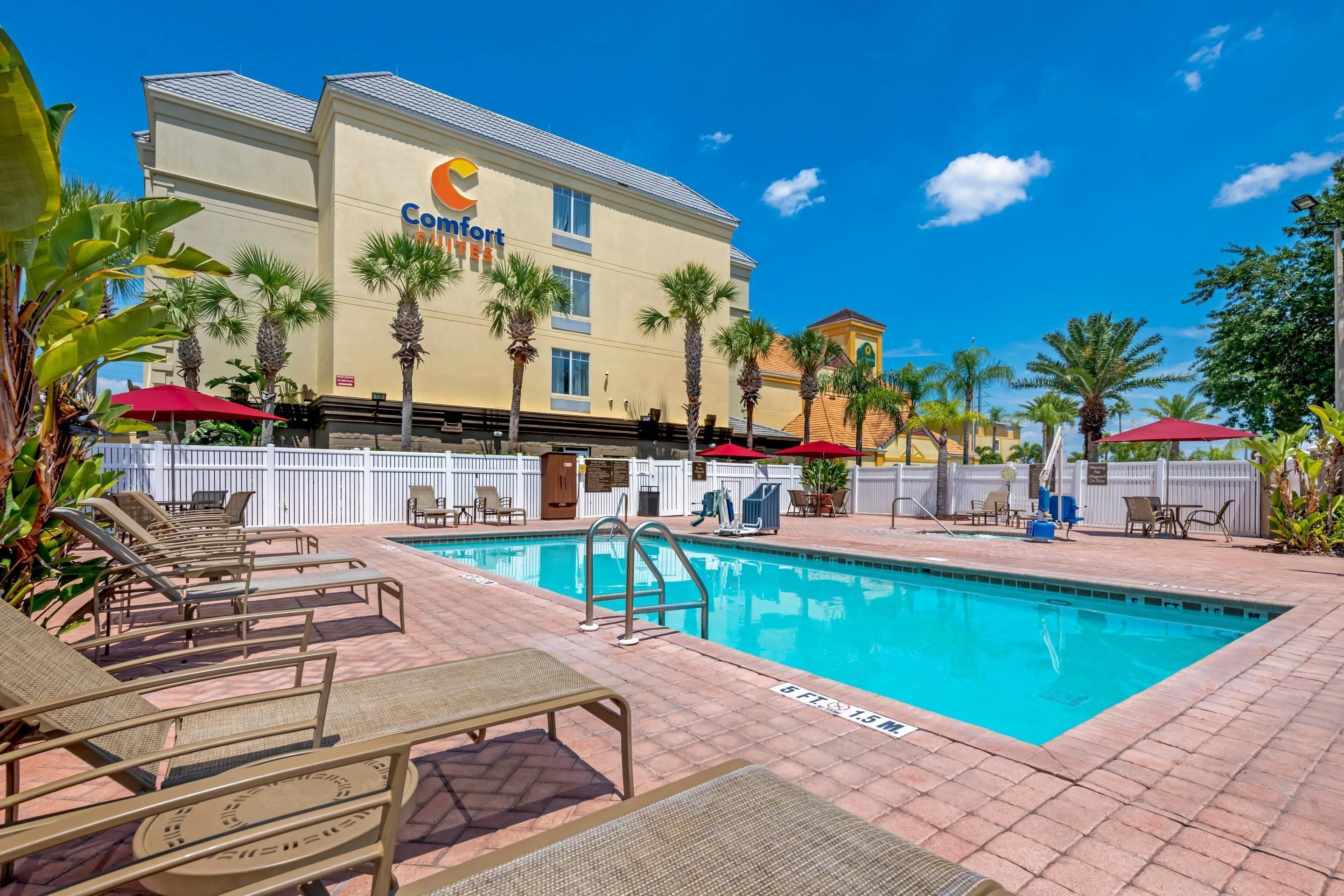 A hotel with a pool area, palm trees, and lounge chairs.