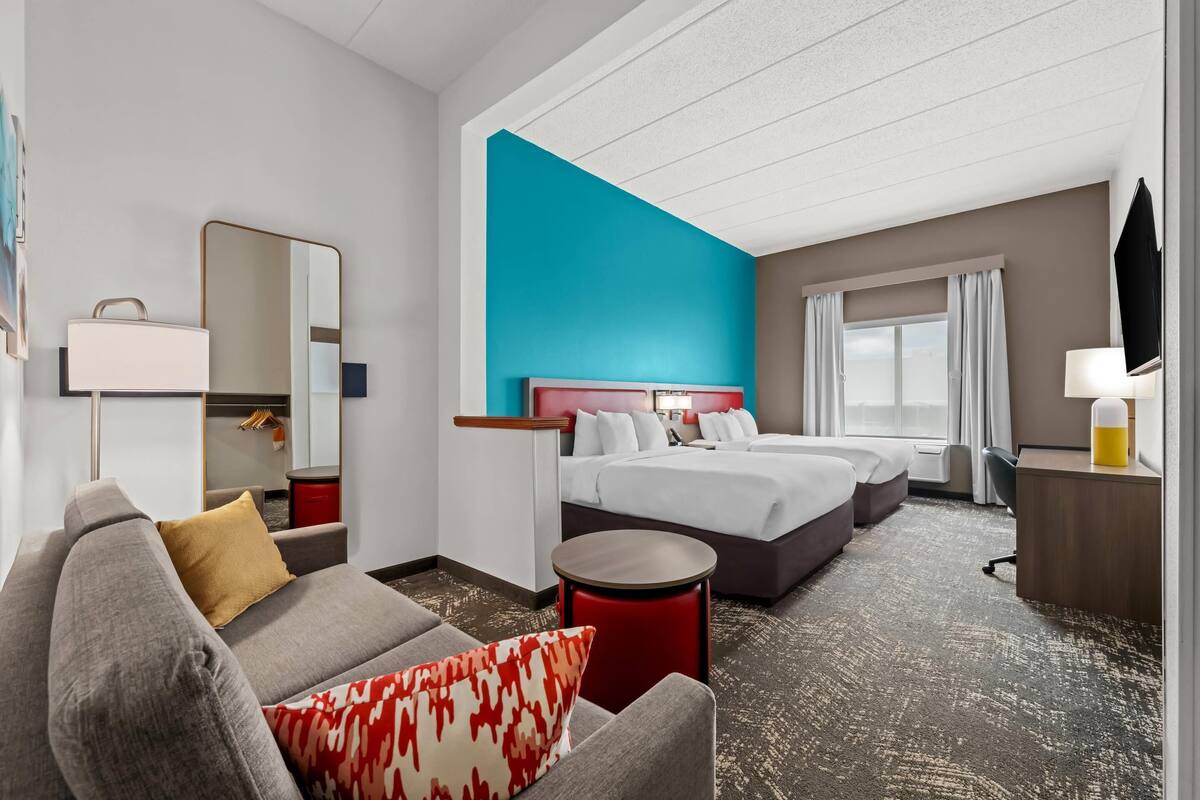 A hotel room with a large bed, a sofa, a small table, and a TV.