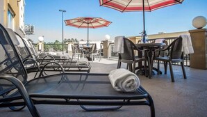 A rooftop terrace with outdoor seating, including lounge chairs and tables, under striped umbrellas. - Comfort Suites Columbia at Harbison (Columbia)