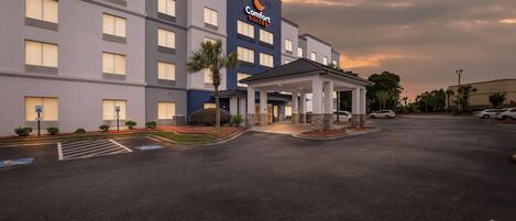 A Comfort Suites hotel with a modern facade, a covered entrance, and a parking lot.