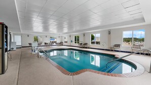 An indoor swimming pool with a tiled floor, a poolside area with chairs, and large windows offering a view of the outdoors. - Comfort Suites Columbia at Harbison (Columbia)