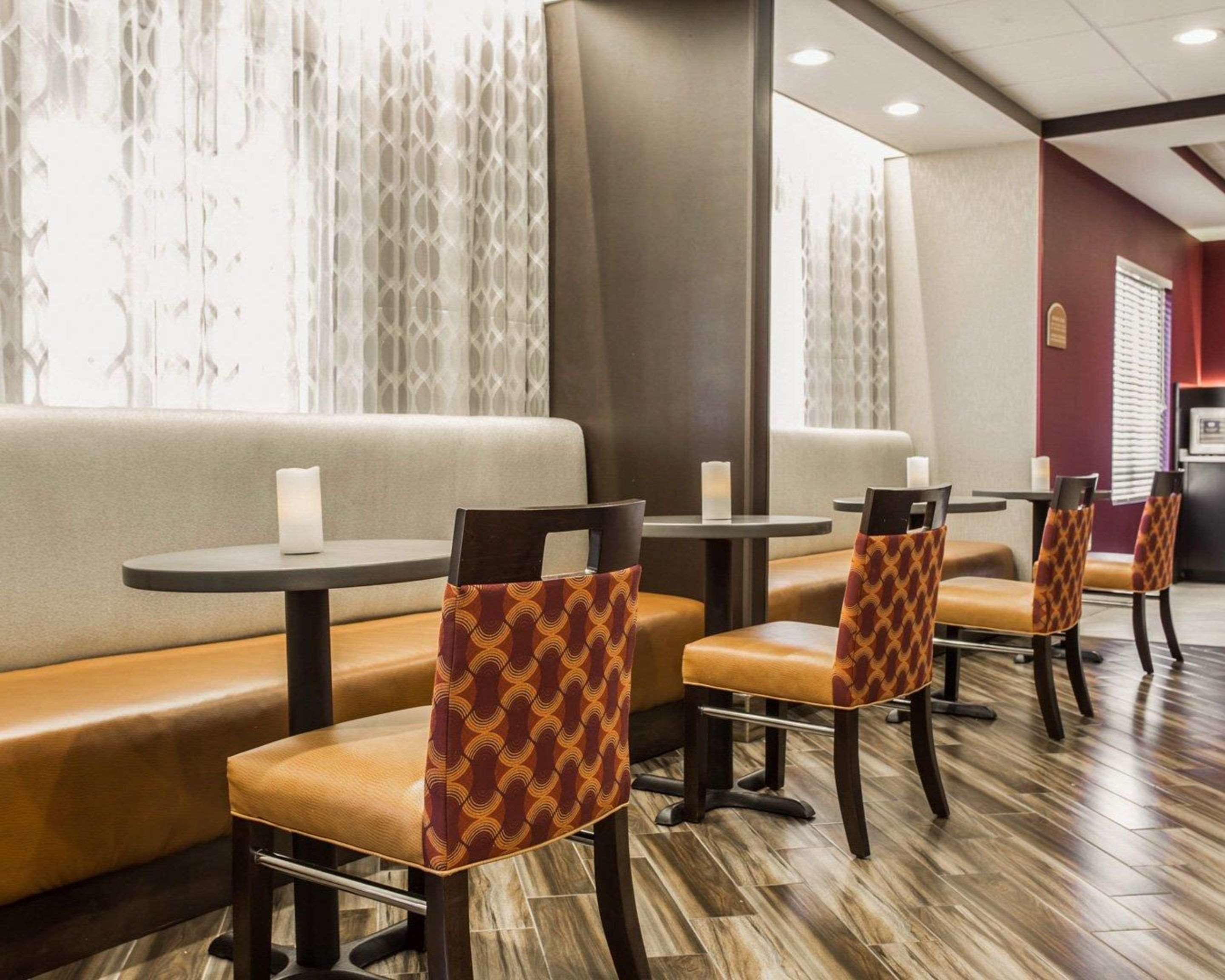 A restaurant with booths and tables, featuring patterned chairs and a wooden floor.