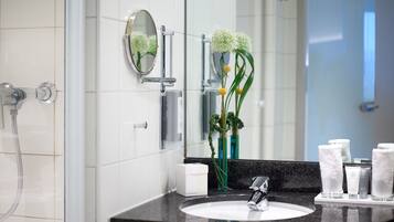 Un baño moderno con un lavabo blanco, un espejo y una ducha.
