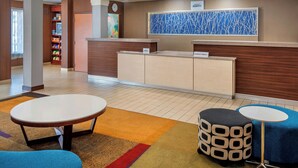 A hotel lobby with a reception desk, a clock, a colorful abstract painting, and a reception area with a counter and cabinets. - Fairfield Inn & Suites by Marriott Dover (Dover)