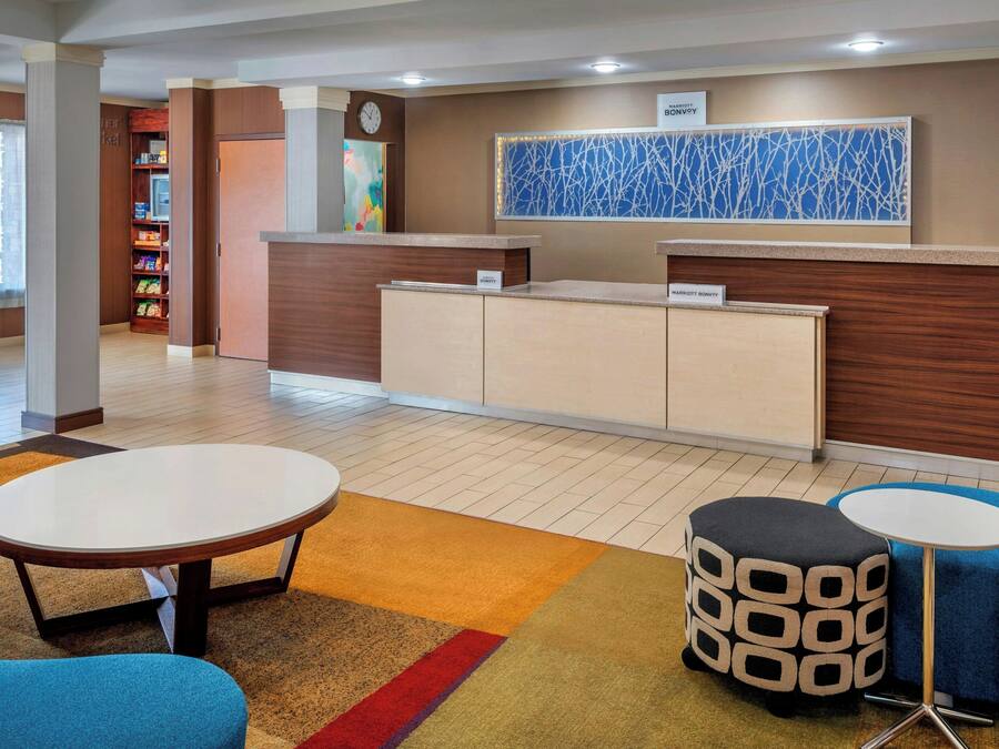 A hotel lobby with a reception desk, a clock, a colorful abstract painting, and a reception area with a counter and cabinets.