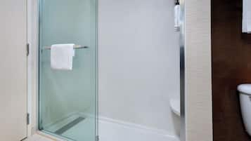 Un baño moderno con ducha envuelta en vidrio, un inodoro blanco y un perchero para toallas.