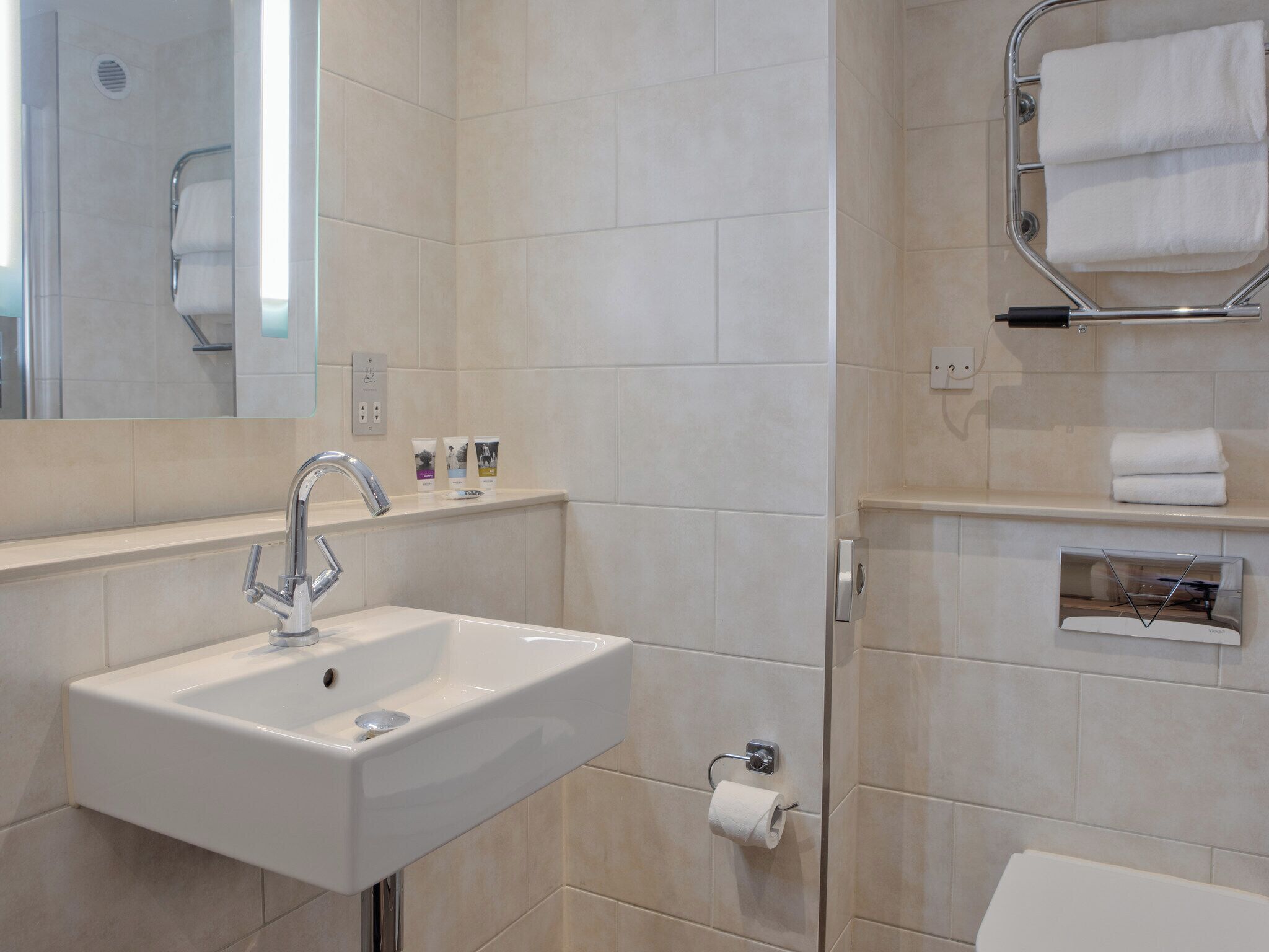 A modern bathroom with a white sink, a towel rack, and a toilet.
