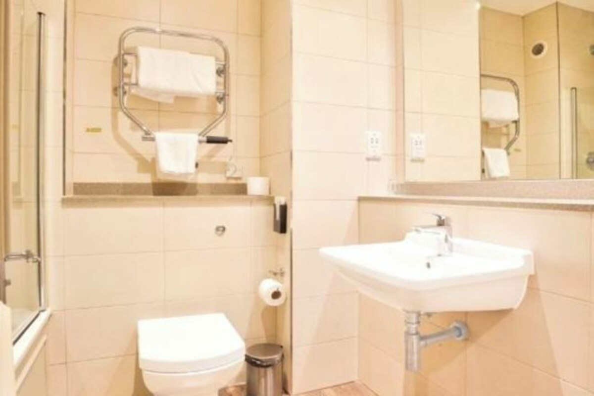 A bathroom with a toilet, sink, and handrails.