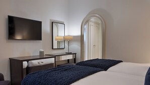 Habitación de hotel con cama, escritorio con silla, televisor de pantalla plana, espejo y puerta.