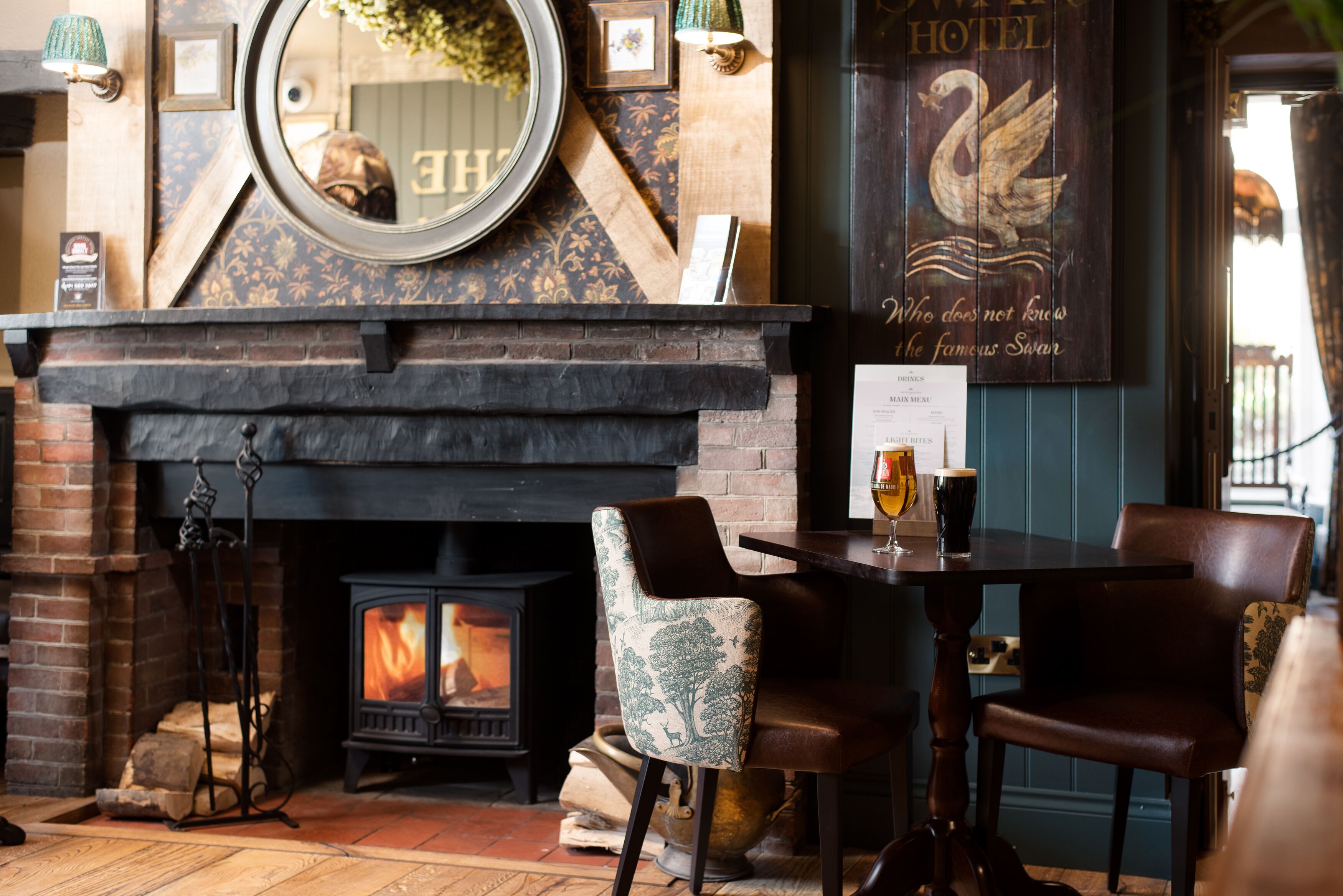 A cozy room with a fireplace, a mirror, and a sign featuring a swan.