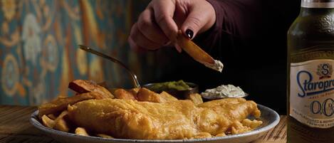 A plate of fish and chips with a bottle of beer.