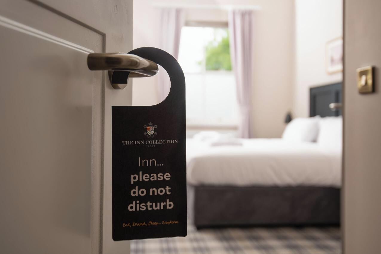 Une porte de chambre d’hôtel avec une pancarte indiquant : « The Inn Collection : veuillez ne pas déranger. »