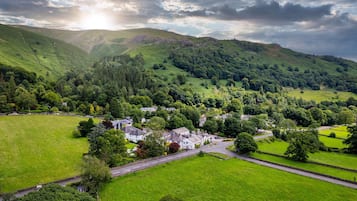 A rural village with houses surrounded by lush green fields and hills.