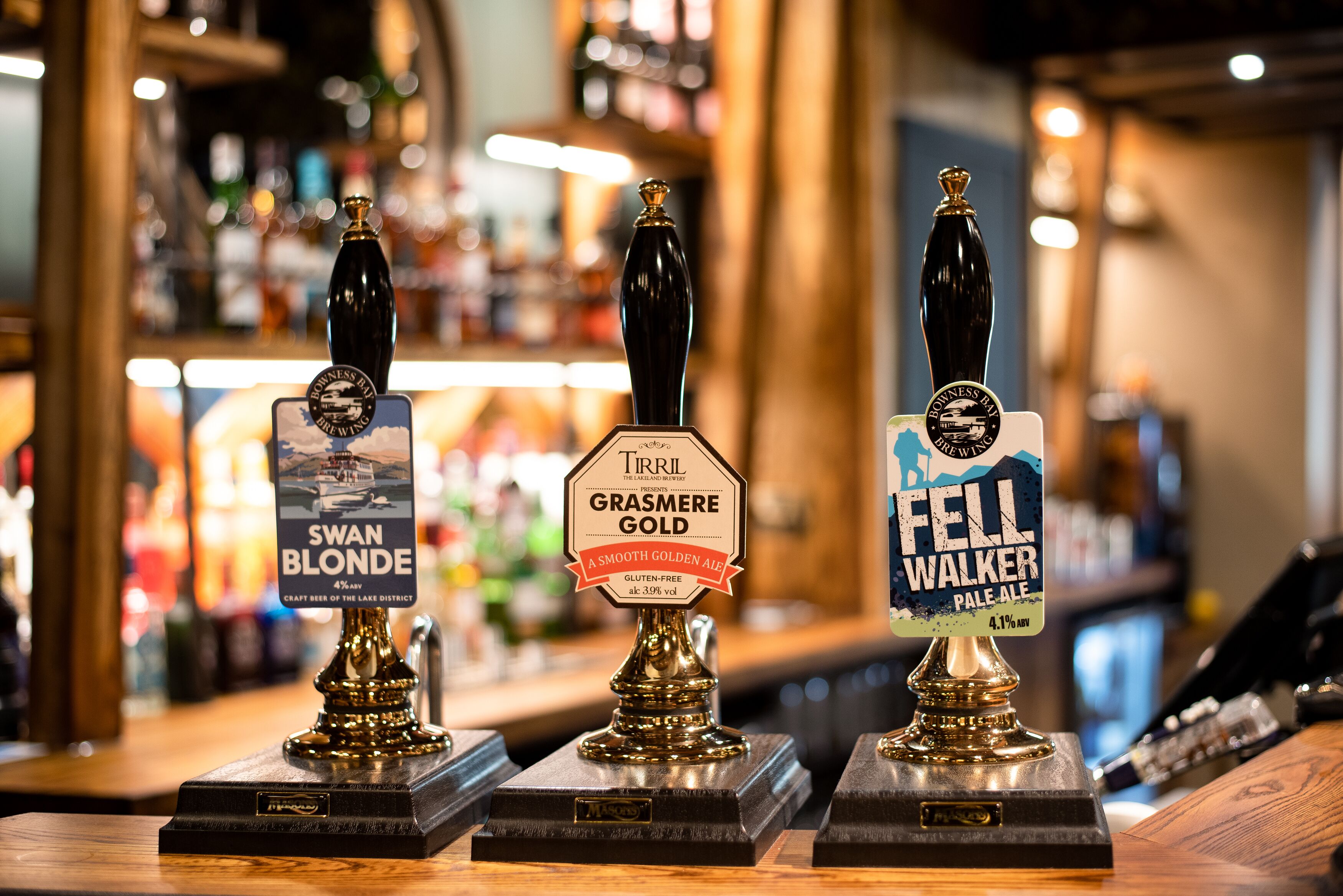 Three beer taps with labels for Swan Blonde, Grasmere Gold, and Fell Walker Pale Ale.