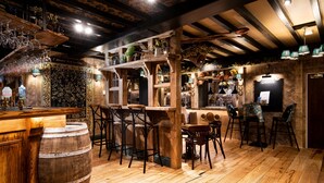 A rustic bar area with wooden furniture, a bar counter, and a variety of bar stools. - The Swan at Grasmere - The Inn Collection group (Ambleside)