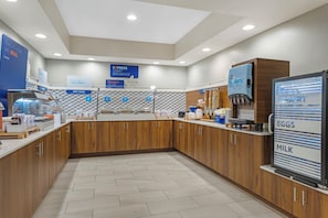 Un espace moderne dédié au petit-déjeuner, avec des meubles en bois, un distributeur de yaourts et une machine à café.