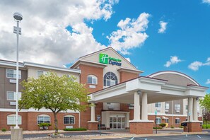 A hotel with a brick facade, a covered entrance, and a clear blue sky. - Holiday Inn Express Hotel & Suites Charlotte by IHG (Charlotte)