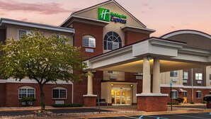 A Holiday Inn Express building with a brick facade, large entrance, and covered parking area. - Holiday Inn Express Hotel & Suites Charlotte by IHG (Charlotte)
