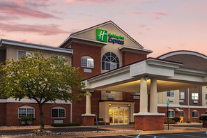 Un bâtiment de la chaîne Holiday Inn Express, avec une façade en briques, une grande entrée et un espace de stationnement couvert.