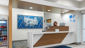 Un comptoir d’accueil agrémenté d’une décoration murale géométrique bleue, un réfrigérateur rempli de boissons et une moquette bleue.
