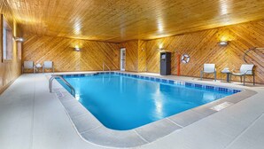 An indoor swimming pool with wooden walls and ceiling, a tiled floor, and a few chairs around the pool. - Holiday Inn Express Hotel & Suites Charlotte by IHG (Charlotte)