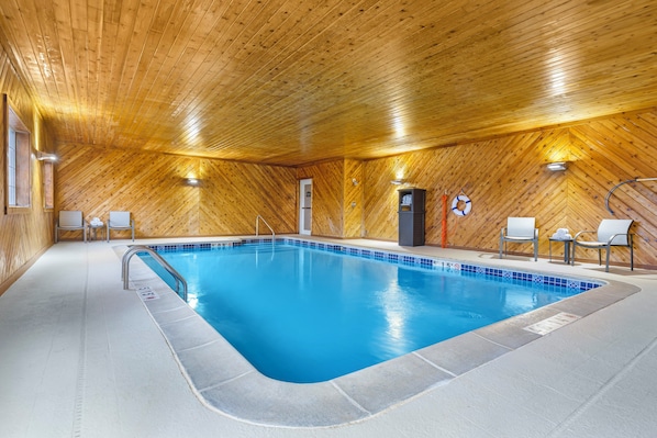An indoor swimming pool with wooden walls and ceiling, a tiled floor, and a few chairs around the pool. - Holiday Inn Express Hotel & Suites Charlotte by IHG (Charlotte)
