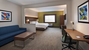 A hotel room with a bed, a desk, a chair, a sofa, and artwork on the walls. - Holiday Inn Express Hotel & Suites Cedar Park by IHG (Cedar Park)