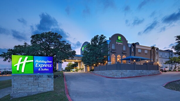 A Holiday Inn Express & Suites with a large sign, a parking lot, and a building with a dome and arched windows. - Holiday Inn Express Hotel & Suites Cedar Park by IHG (Cedar Park)