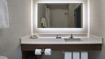 Un baño moderno con un espejo grande, un lavabo blanco y un mueble de tocador de madera.