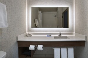 Un baño moderno con un espejo grande, un lavabo blanco y un mueble de tocador de madera.