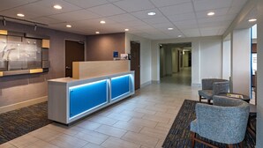 A hotel reception area with a reception desk, a waiting area with chairs, and a hallway leading to other rooms. - Holiday Inn Express Hotel & Suites Cedar Park by IHG (Cedar Park)