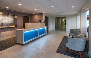 A hotel reception area with a reception desk, a waiting area with chairs, and a hallway leading to other rooms. - Holiday Inn Express Hotel & Suites Cedar Park by IHG (Cedar Park)
