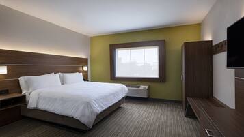 A hotel room with a bed, bedside tables, a TV, and a window with blinds.